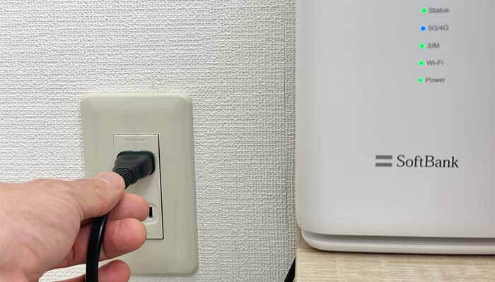 ホームルーターのACプラグをコンセントに挿している写真